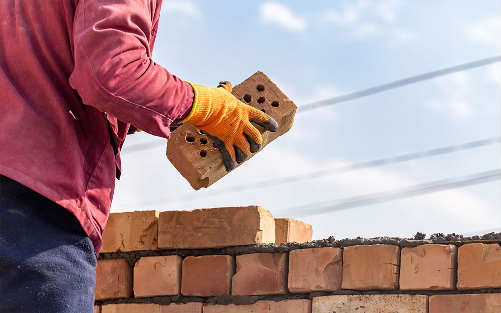 builder assembling brick wall